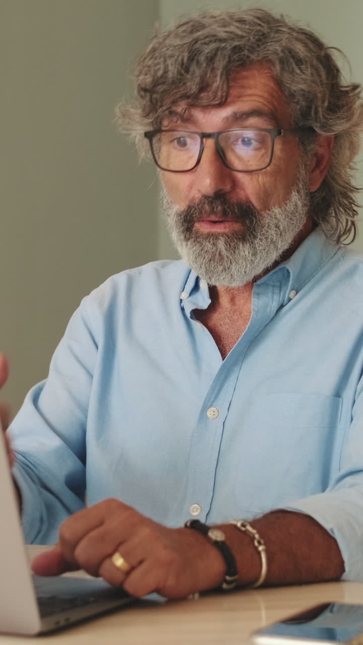 Uomo maturo felice che ride e parla durante una videochiamata sul laptop