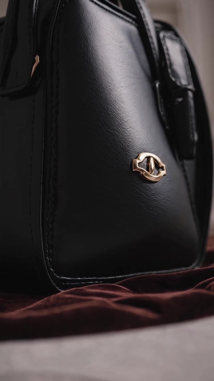 Elegante borsa in pelle nera con dettagli dorati in rotazione