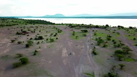 traveler riding motorcycle through idyllic landscape of lake magadi in kenya - aerial pullback