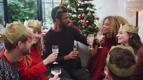 group of friends celebrating with champagne after enjoying christmas dinner at home