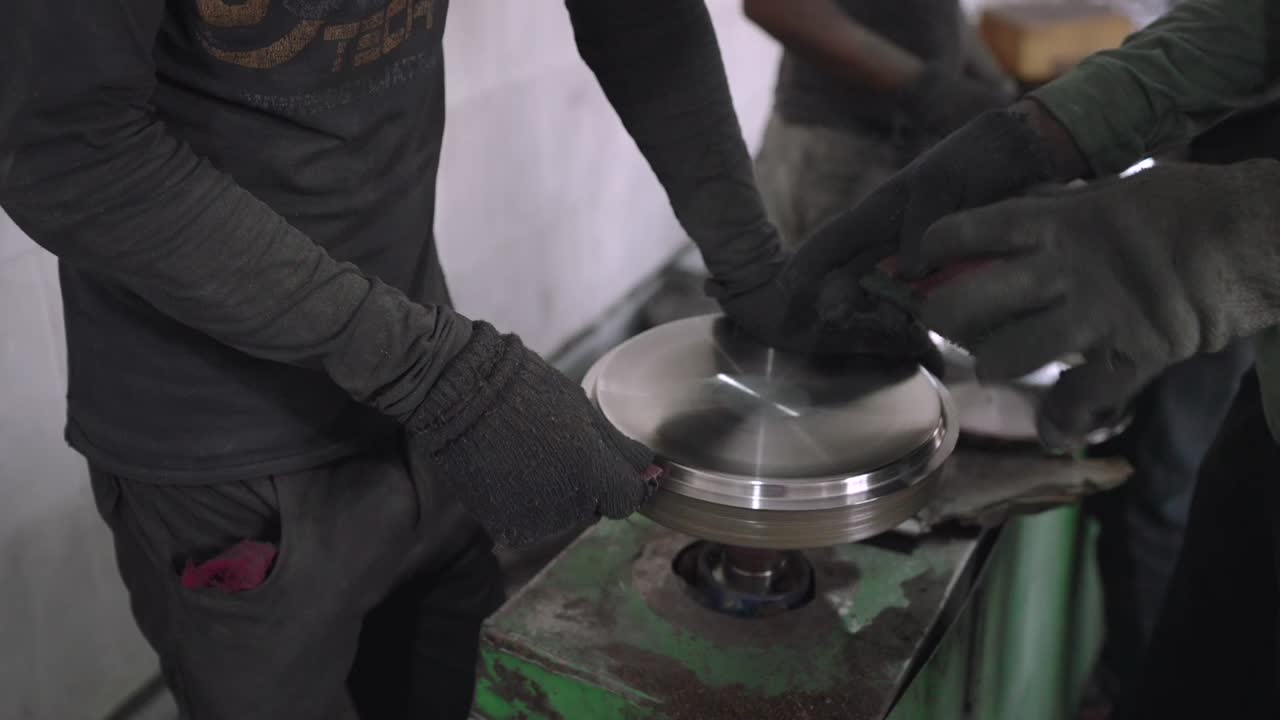Using a belt sander to produce steel pan cookware in a factory