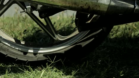 close up of motorcycle wheel stopping and foot getting off bike