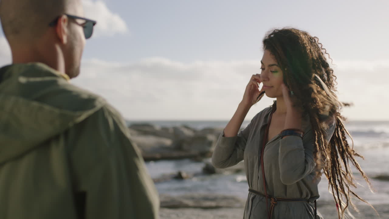 아름다운 혼혈 여성이 해변에서 사진을 찍는 사진 커플을 위해 포즈를 취하고 있습니다.