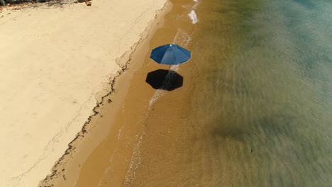 aerial drone orbiting rotating shot of lonely sun umbrella in the sand of a beautiful desert beach in remote island