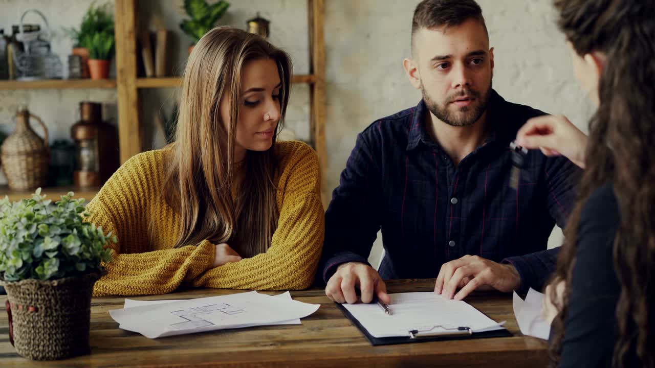 el comprador de una casa está firmando un acuerdo de venta con un agente de vivienda, obteniendo la llave y abrazando a su novia después de hacer un trato con un agente inmobiliario.
