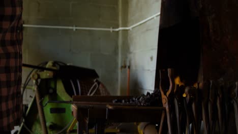 female metalsmith heating horseshoe in fire 4k