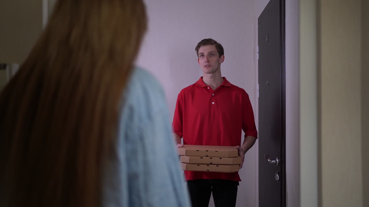 una mujer caucásica abre las puertas y conoce al mensajero de pizza.