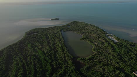 Holbox-island-in-mexico,-showcasing-lush-greenery-and-serene-waters-at-golden-hour,-aerial-view