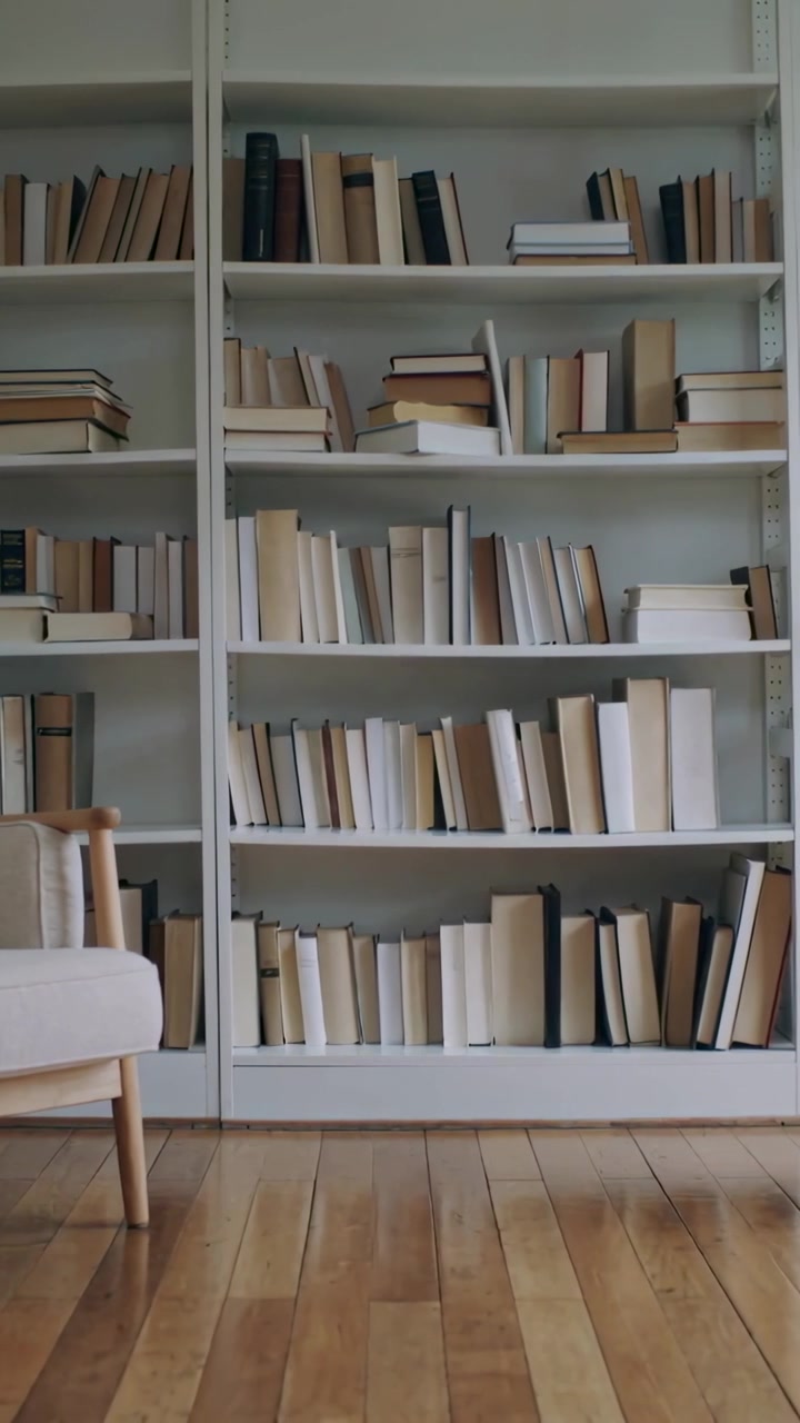 Vertical video: Shifting camera right and up to center white bookcase at home, showing armchair