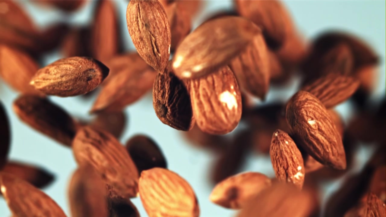 Delicious Almonds Falling in Slow Motion Against a Blue Background