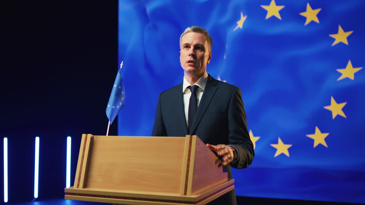 Mature Politician Reassuring Audience during Speech Pan around Middle Aged Male in Suit Gesticulating and Talking with Audience while Standing on Rostrum against European Flag