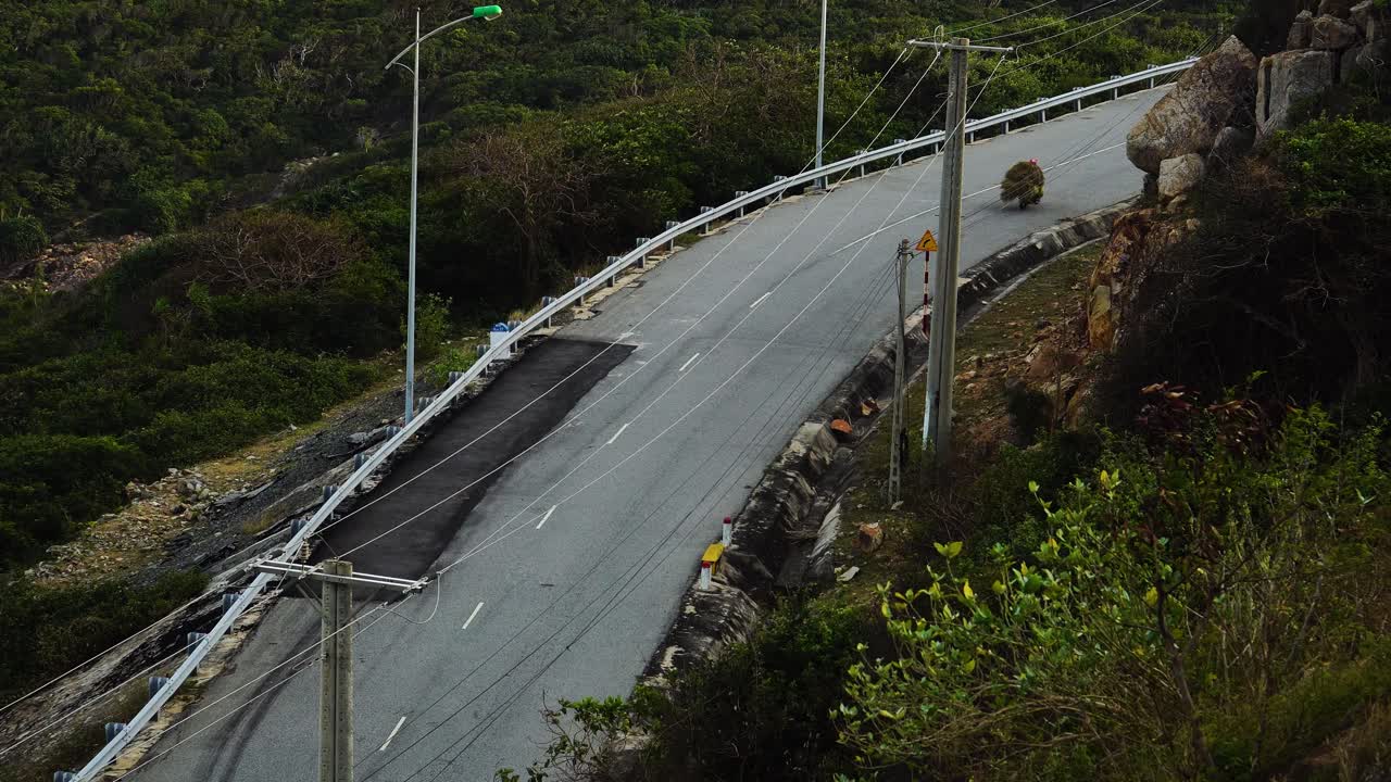 적재된 오토바이와 함께 지나가는 인식할 수 없는 바이커의 정적 낮은 각도 샷
