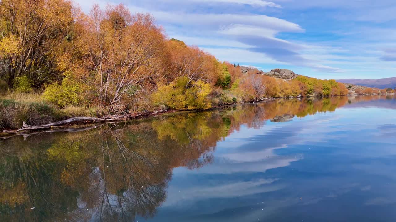 Aerial view of Lake Dunstan's autumn landscape with vibrant foliage and serene reflections under clear skies