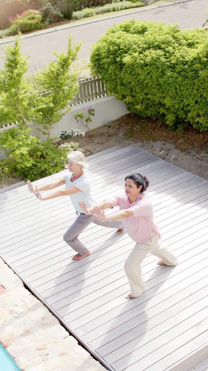 To glade, forskellige ældre kvinder, der dyrker yoga i solrig have, slowmotion