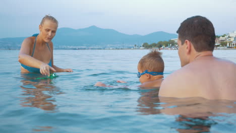 Familie-Spielt-Mit-Spielzeugfrosch-Im-Meer