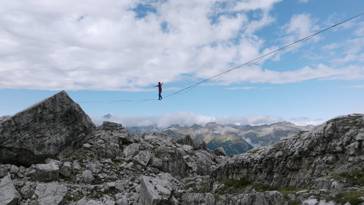 toma aérea de un highliner caminando sobre una cuerda floja y cayendo en las montañas