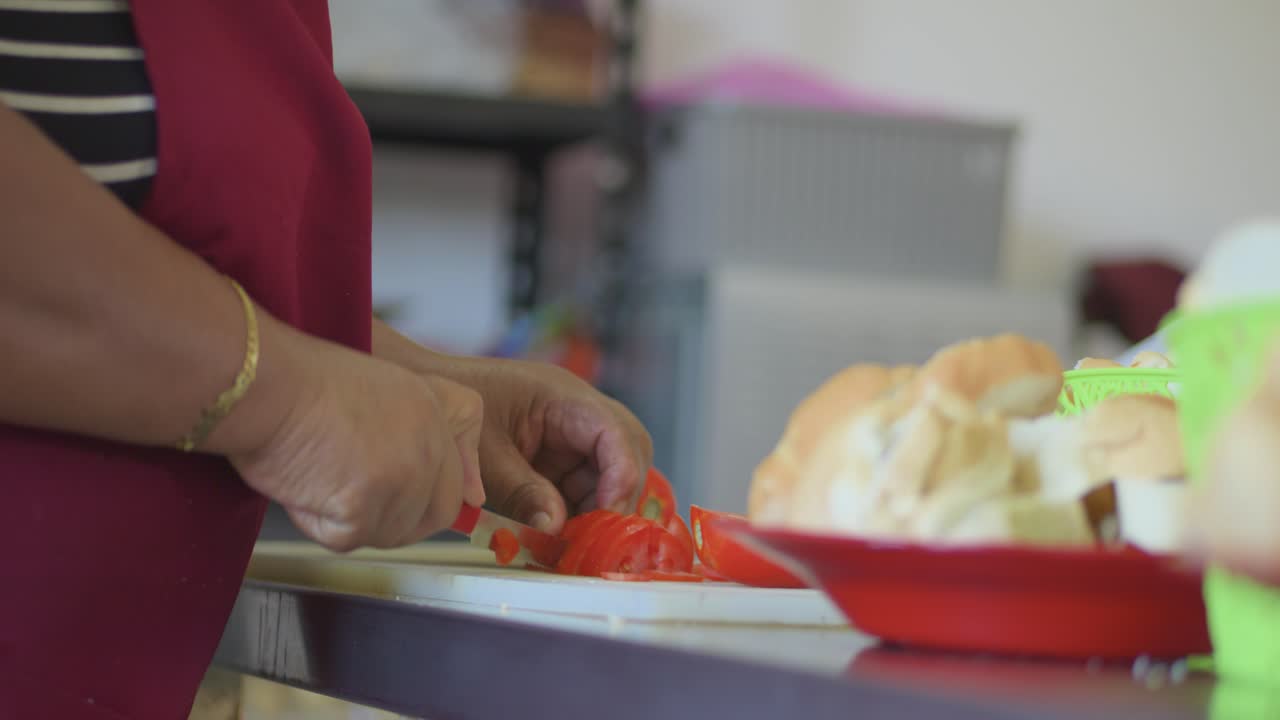Una donna sta tagliando un pomodoro su un tagliere. Concetto di calma e concentrazione mentre la donna affetta attentamente il pomodoro