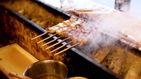 meat skewers cooking on a smoky charcoal grill