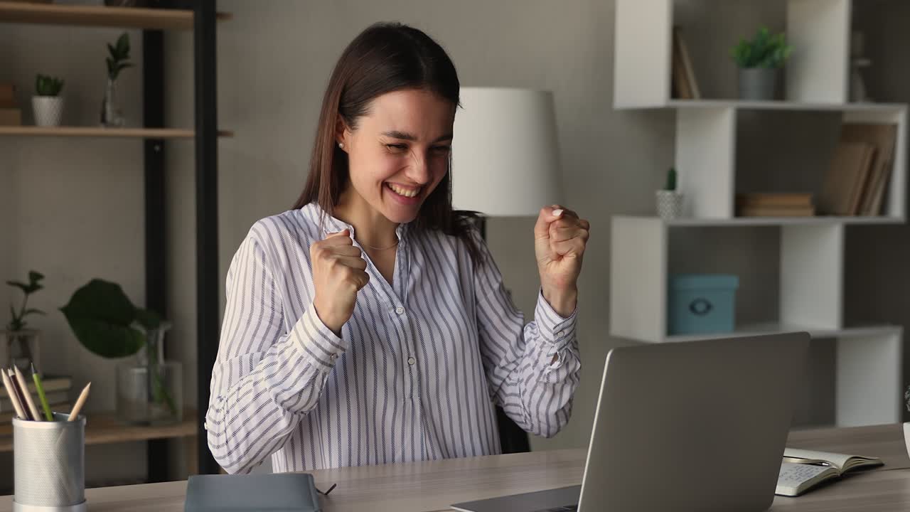 Euphoric young female entrepreneur celebrating business achievement.