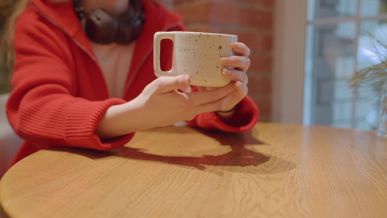 Mani che tengono una tazza di ceramica calda in un ambiente da caffè