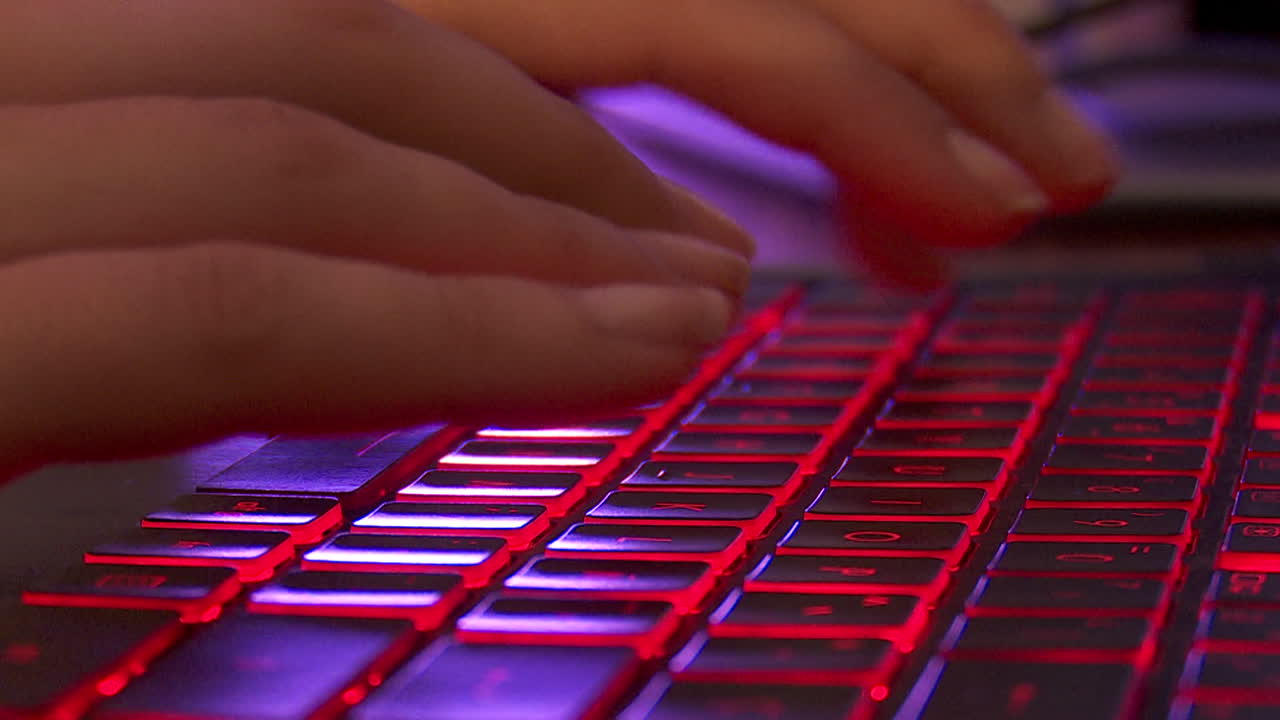 Person typing on a backlit keyboard