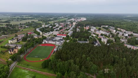 sideways drone view reveals entire olaine city surrounded by green nature