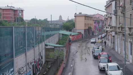 suburb street with graffiti, people and cars parked in milan, view from above