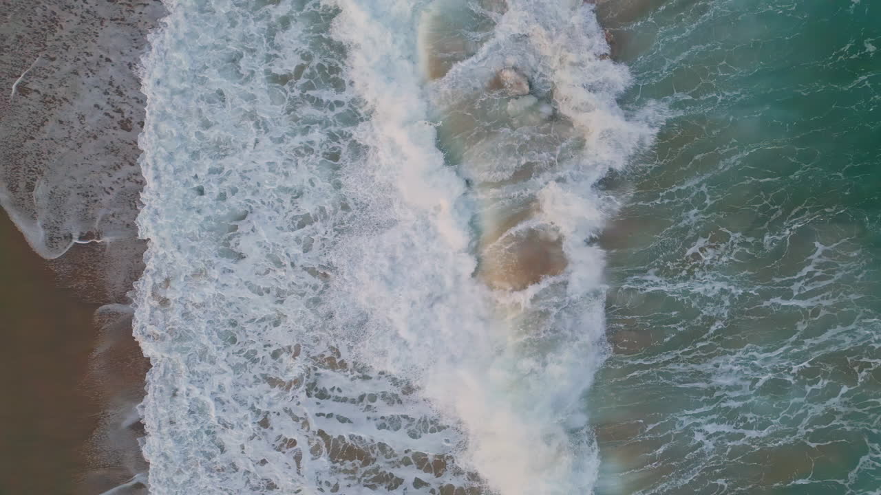 Aerial view foaming sea water splashing rolling top shot. Waves washing seashore