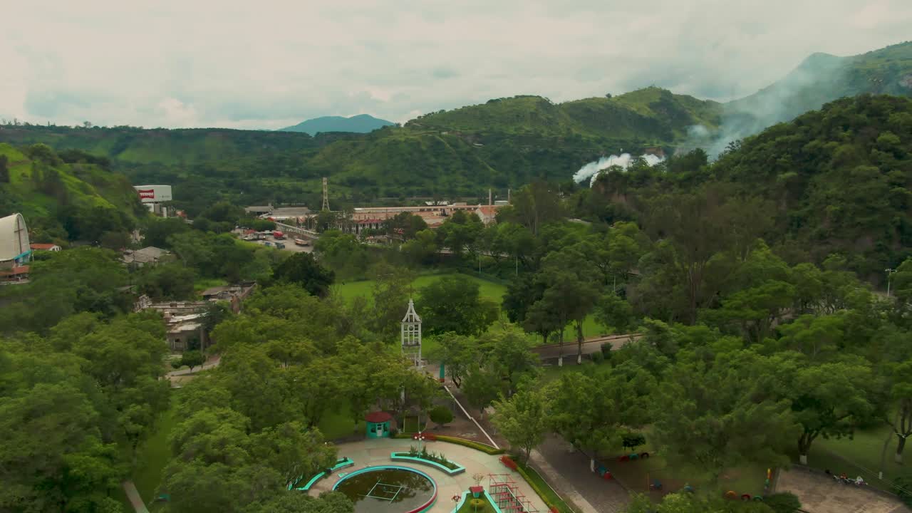 Ripresa con drone di Atenquique, Jalisco, con una ciminiera di fabbrica e un pennacchio di fumo bianco in lontananza.