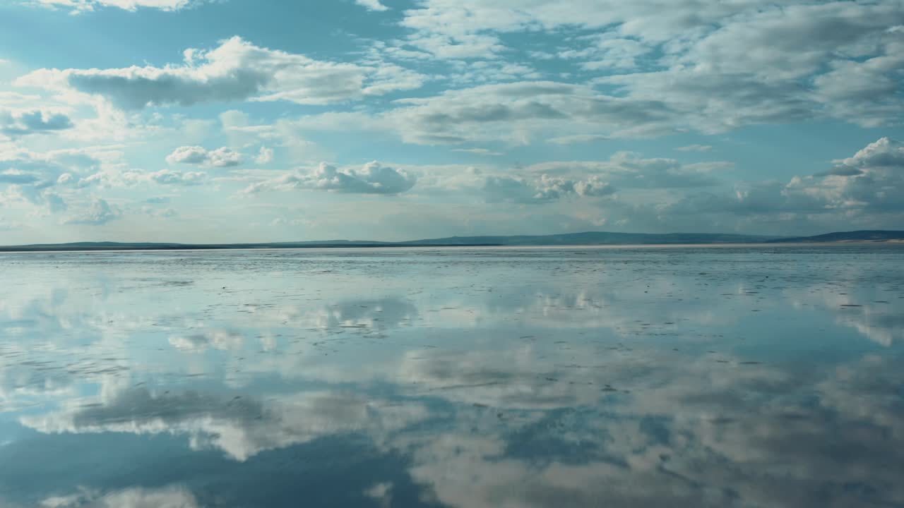низкий вид с воздуха на соленое озеро, отражающее голубое небо и облака