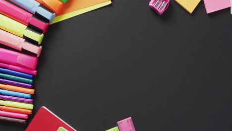 video of school supplies and notebooks, paper clips, pens over black background