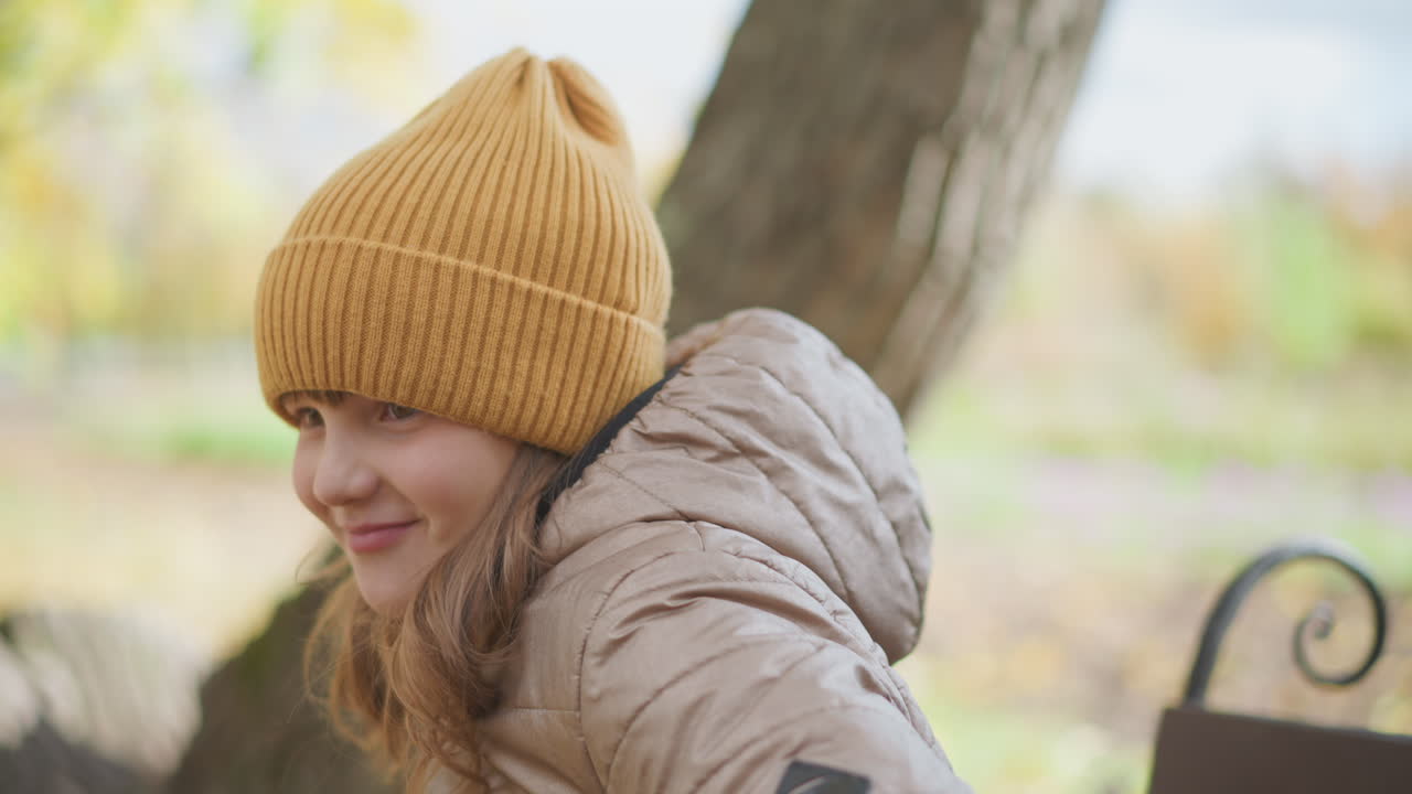 little girl offers yellow leaves to distract mother working on laptop in autumn park but mother continues typing without looking, prompting child to step back and withdraw with gentle resignation