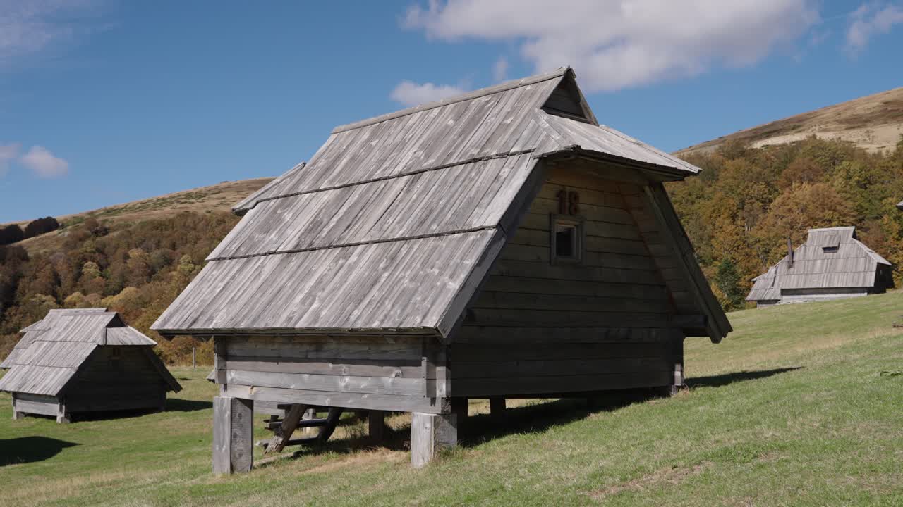 Rustic wooden huts in Kolašin, Montenegro under a bright blue sky
