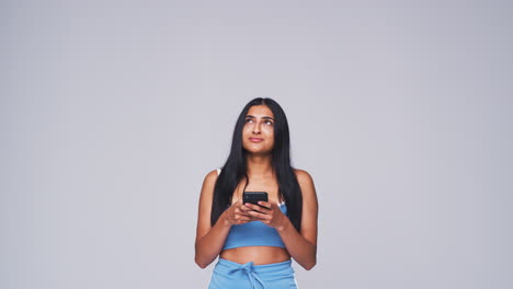 Foto-De-Estudio-De-Una-Mujer-Con-Fondo-Blanco-Enviando-Mensajes-De-Texto-Por-Teléfono-Móvil-En-Cámara-Lenta