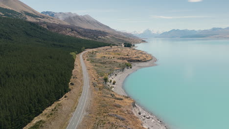 aerial view of a road along a turquoise lake in new zealand