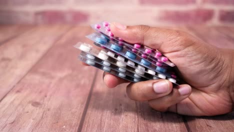 hand holding stacked blister packs of assorted pills