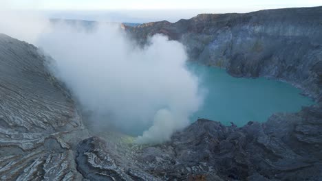 toxic sulfuric gases rising from ijen crater in indonesia. aerial view. early morning dawn
