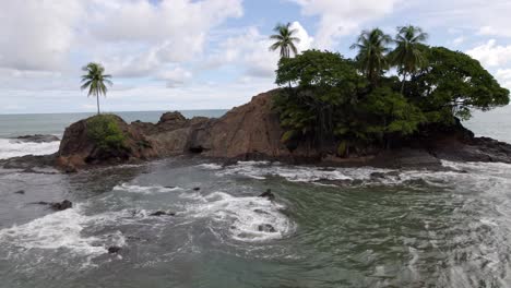 camión aéreo a la izquierda de la escarpada costa rocosa y las espumosas olas del mar en un día nublado en la playa dominicalito, costa rica