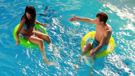 couple sitting on inflatable rings in the swimming pool