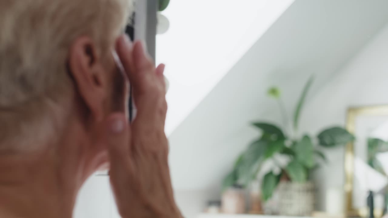 Senior woman about to apply an eye cream.