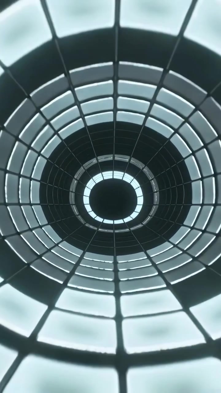 Video verticale: Piastrelle che si separano, telecamera che si muove in un pozzo verso un anello illuminato al suo interno, con una griglia metallica.