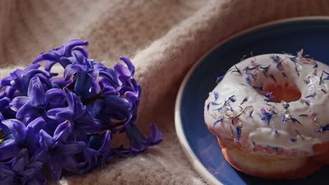 Tea-Time-Dessert,-Donut-Mit-Blumenstreusel-Und-Blauer-Hyazinthe-Auf-Flauschigem-Tuch