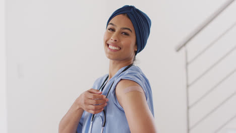 video of happy biracial woman in hijab showing plaster after vaccination