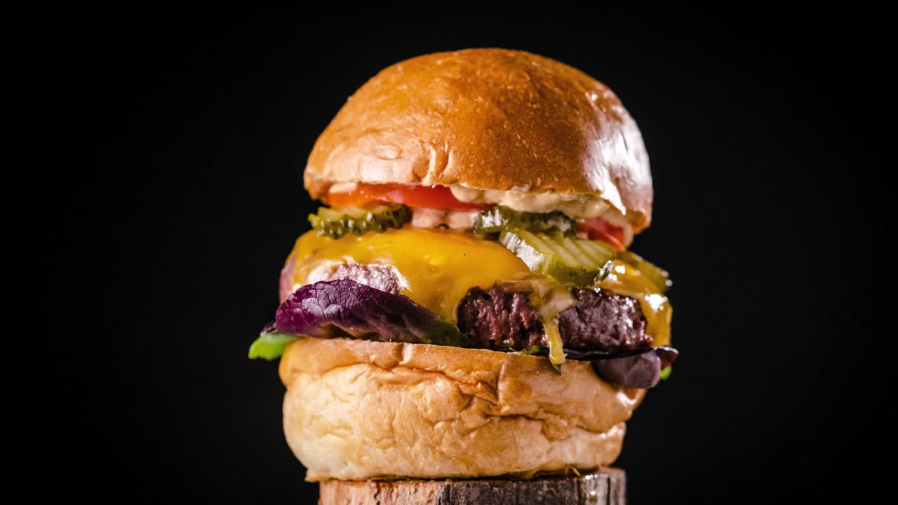 Tasty big burger rotating on wooden board. Stop motion