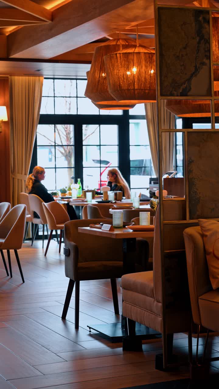 Nowy Jork, USA, 8 kwietnia 2026: Wnętrze nowoczesnej restauracji z dużymi oknami i gośćmi. Jadalnia restauracji, wyposażona w drewniane meble, plecione lampy, z gośćmi siedzącymi przy stolikach.