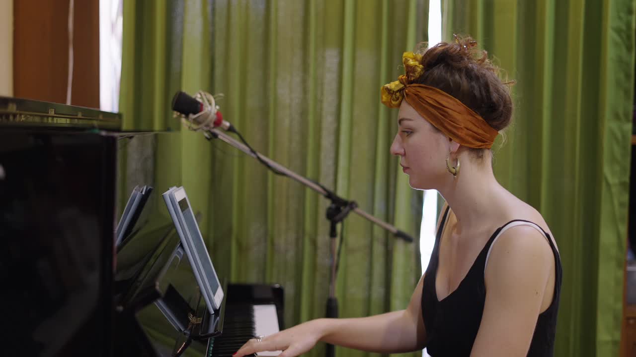 Musician playing piano with a tablet in a recording studio