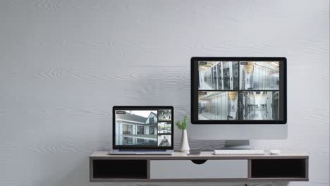 wall mounted computer monitor and laptop on desk with security camera views on screens, slow motion