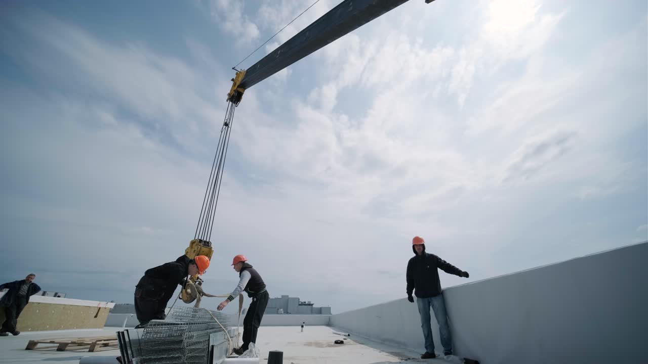 건설 타워 크레인은 지붕에 짐을 들어 올리고 있습니다.