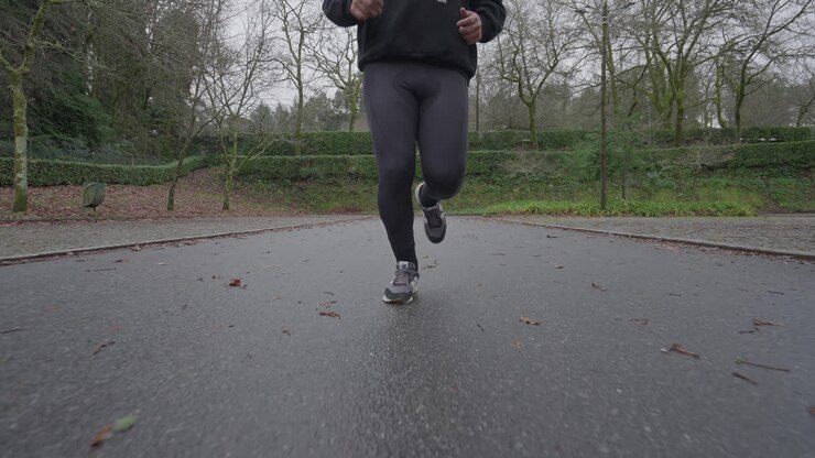 Man running toward camera in slow motion on wet park pavement