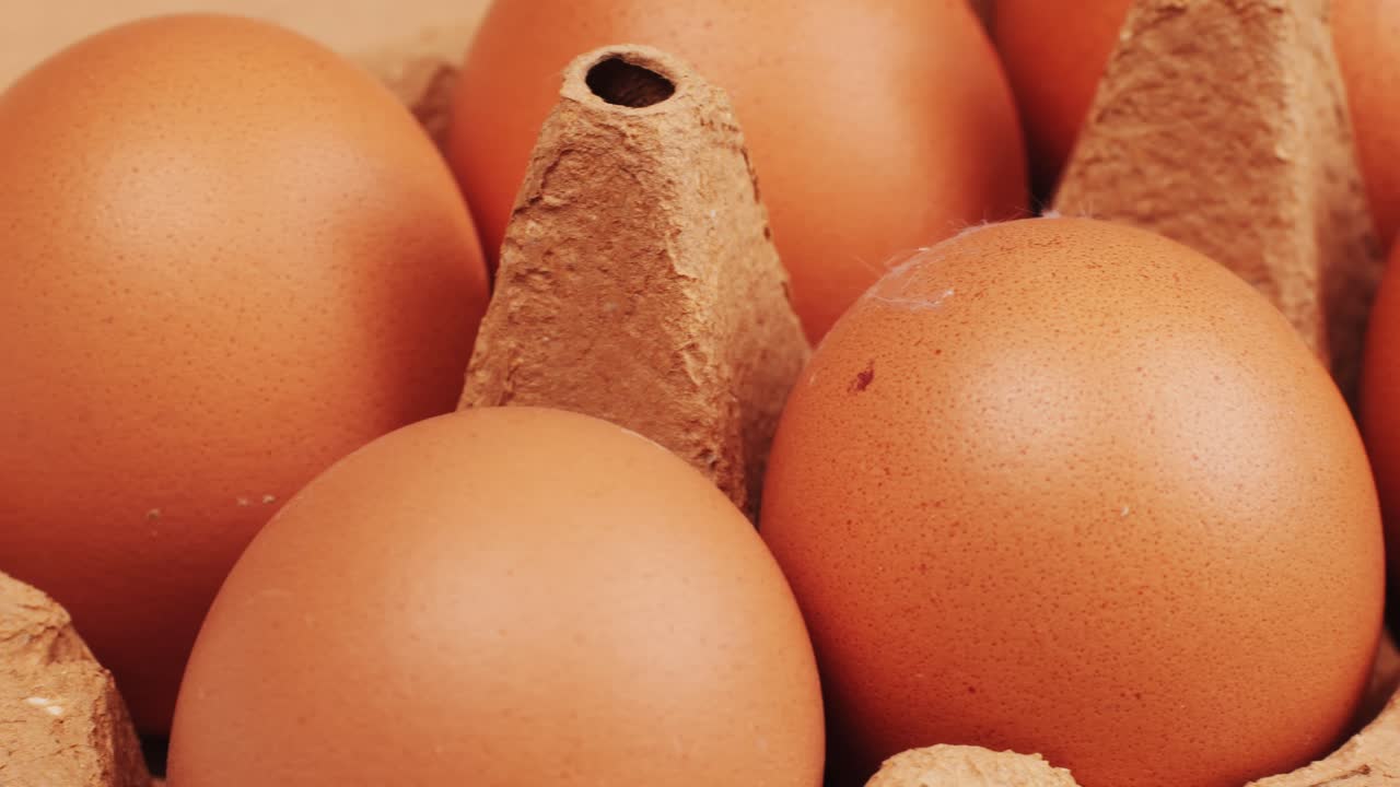 Fresh chicken eggs and dried straw on black wooden table, closeup. High quality 4k footage